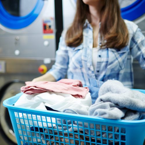 Woman holding heap of clothes in laundry basket